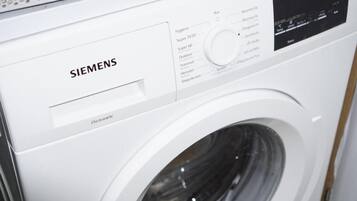 Une machine à laver Siemens blanche, dotée d’un panneau de commande et d’un écran numérique.