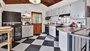 A kitchen with a checkered floor, white cabinets, stainless steel appliances, and a wooden ceiling. - Gorgeous mountain view cabin rental, hot tub, firepit, WiFi, pet-friendly (Ellijay)