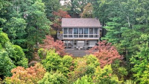 A two-story house surrounded by dense forest with a visible deck and outdoor seating area. - Gorgeous mountain view cabin rental, hot tub, firepit, WiFi, pet-friendly (Ellijay)