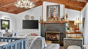 A cozy living room with a fireplace, a television mounted on the wall, and a comfortable seating area with a sofa and armchairs. - Gorgeous mountain view cabin rental, hot tub, firepit, WiFi, pet-friendly (Ellijay)
