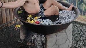 Eine Person entspannt sich in einem Whirlpool im Freien, im Hintergrund eine Bambuskonstruktion.