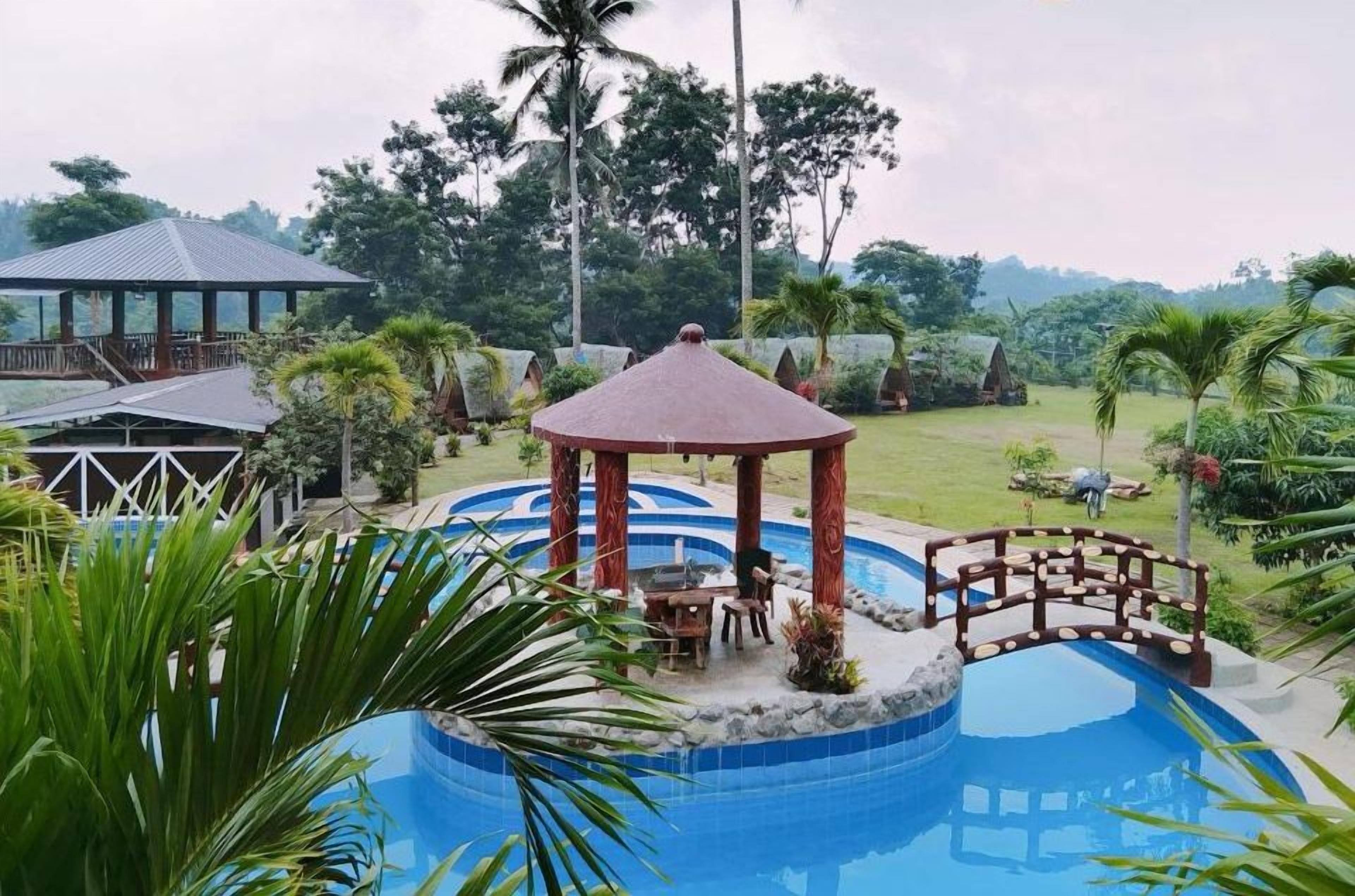 A pool area with a gazebo, palm trees, and a view of the resort's buildings.