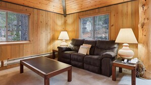 Una habitación acogedora con un sofá de cuero, dos mesitas de noche con lámparas y una mesa de centro de madera.
