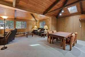 L’intérieur d’un chalet accueillant, avec un plafond en bois, un canapé, une table à manger et deux lampes.
