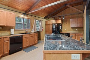 Une cuisine moderne avec des meubles en bois, un plan de travail en granit et un lave-vaisselle encastré.