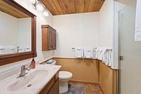 A bathroom with a wooden vanity, a sink, a toilet, and a towel rack with towels. - 7 Bobcat - Hot Tub, SHARC, Close to Village, A/C (Sunriver)