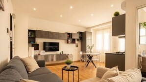 A modern living room with a grey sofa, a coffee table, and a dining area with a glass table and chairs. - Sparano mood 170 - central cozy stay (Bari)