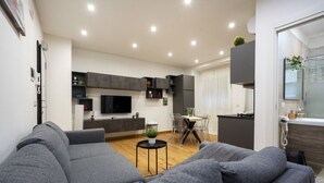 A modern living room with a grey sofa, a flat-screen TV, and a dining area with a table and chairs. - Sparano mood 170 - central cozy stay (Bari)