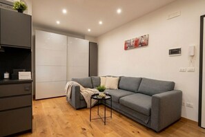 A modern living room with a grey sofa, a small side table, and a wooden floor. - Sparano mood 170 - central cozy stay (Bari)