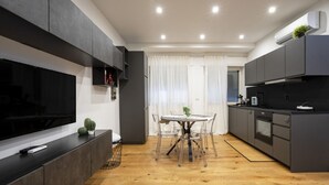 A modern kitchen with dark cabinetry, a wooden floor, and a dining area with a round table and chairs. - Sparano mood 170 - central cozy stay (Bari)