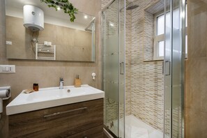 A modern bathroom with a glass shower enclosure, a white sink with a wooden vanity, and a mirror above the sink. - Sparano mood 170 - central cozy stay (Bari)