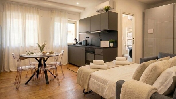 A modern hotel room with a bed, a dining table with chairs, a kitchenette, and a bathroom. - Sparano mood 170 - central cozy stay (Bari)