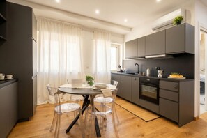A modern kitchen with a dining area, featuring a round table with chairs, a built-in oven, and grey cabinetry. - Sparano mood 170 - central cozy stay (Bari)