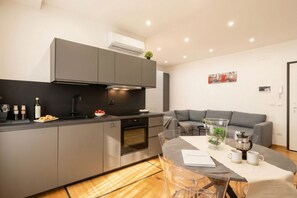 A modern kitchen with grey cabinetry, a built-in oven, and a dining area with a glass table. - Sparano mood 170 - central cozy stay (Bari)