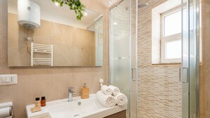A modern bathroom with a large mirror, a white sink, a towel rack, and a glass shower enclosure. - Sparano mood 170 - central cozy stay (Bari)
