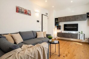 A modern living room with a grey sofa, a small table with a plant, and a flat-screen TV mounted on the wall. - Sparano mood 170 - central cozy stay (Bari)