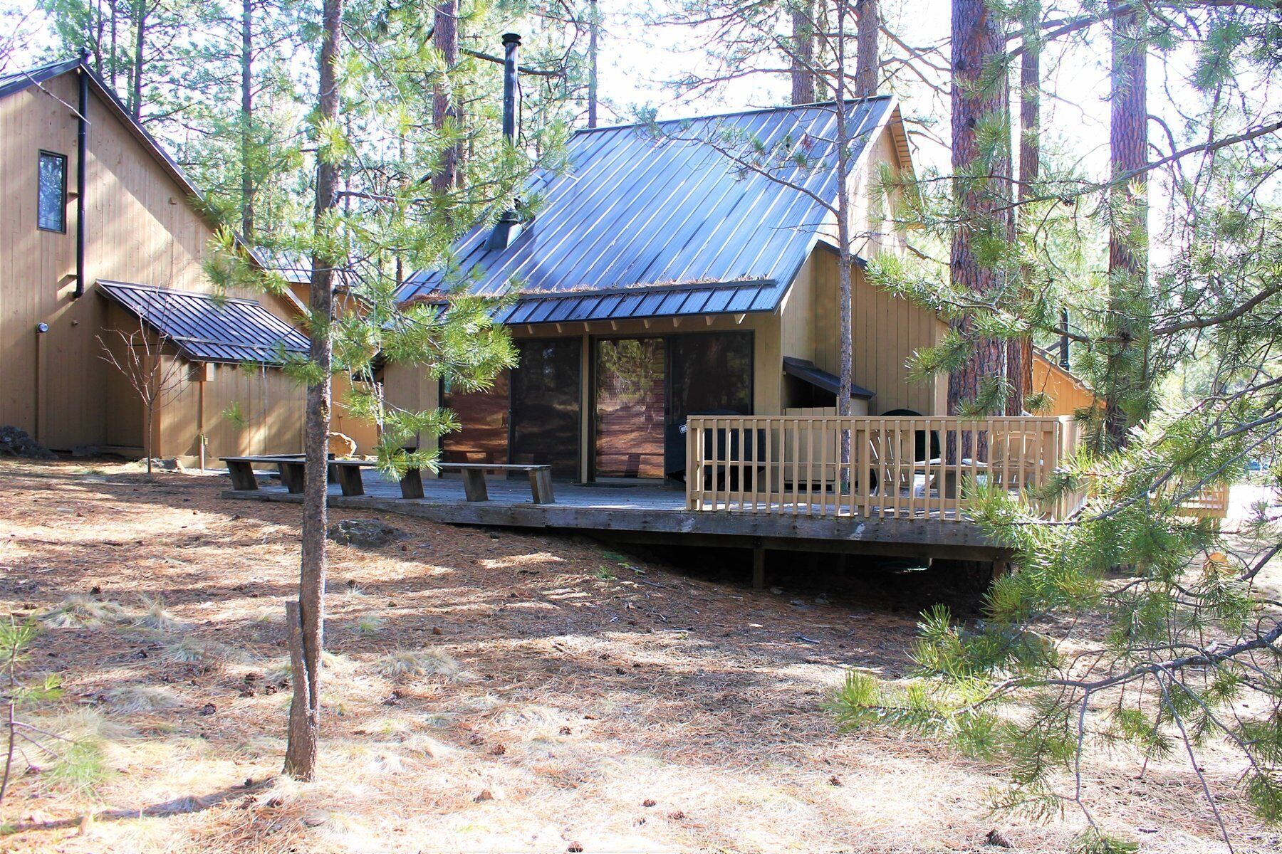 Uma cabana com telhado de metal, deck de madeira e varanda coberta.