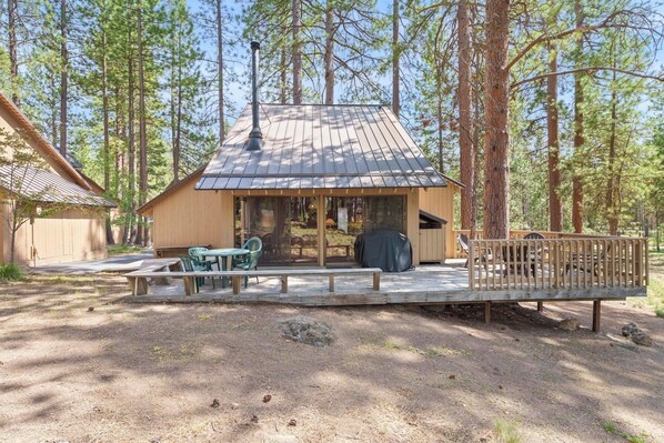 A cabin with a deck, outdoor seating, and a covered area.