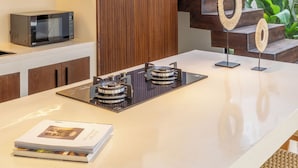A modern kitchen with a central island, built-in appliances, and a wooden accent wall. - La Finca Bingin (Pecatu)