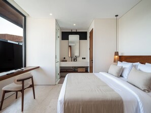 A modern hotel room with a large bed, a desk, and a television. - La Finca Bingin (Pecatu)