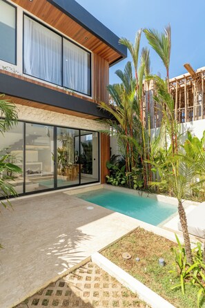 A modern house with a swimming pool, large glass doors, and tropical plants. - La Finca Bingin (Pecatu)