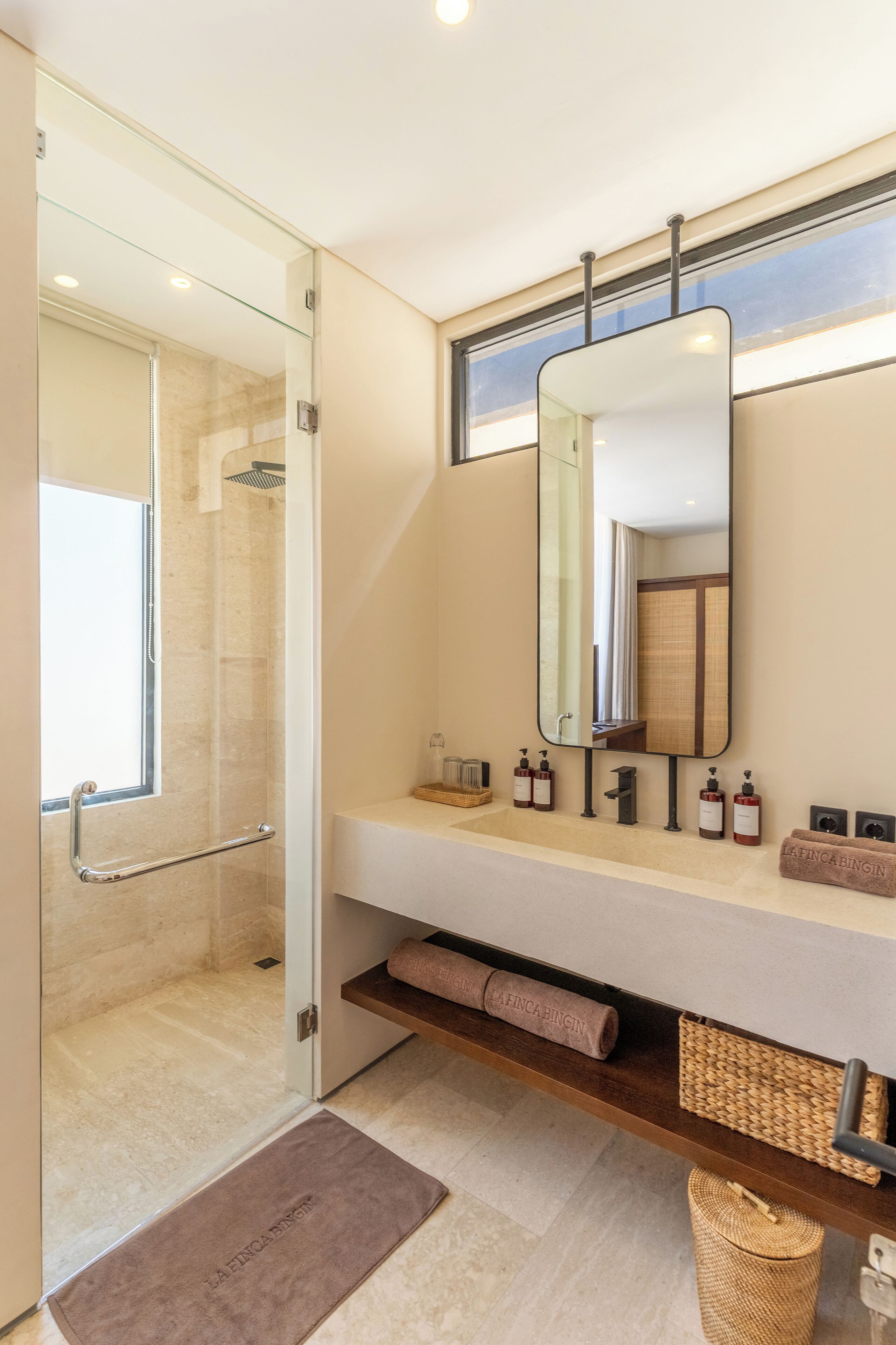 A modern bathroom with a glass shower enclosure, a large mirror, and a vanity with toiletries.