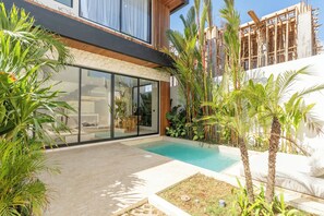 A modern house with a swimming pool, large glass doors, and tropical plants. - La Finca Bingin (Pecatu)