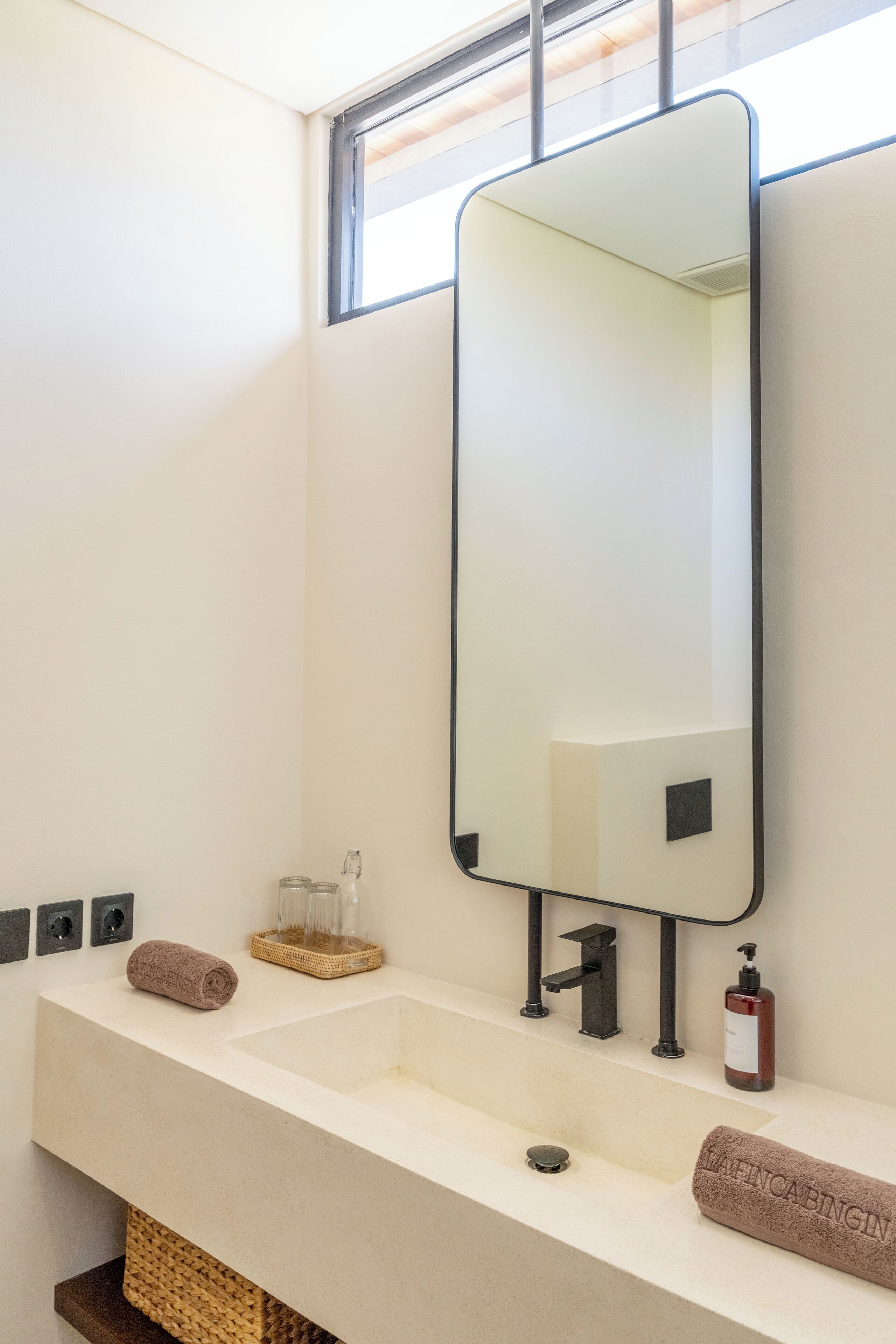 Een moderne badkamer met een grote spiegel, twee wastafels en een raam boven de spiegel.