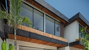 A modern house with a large glass window, a pool, and a staircase leading to a second floor. - La Finca Bingin (Pecatu)
