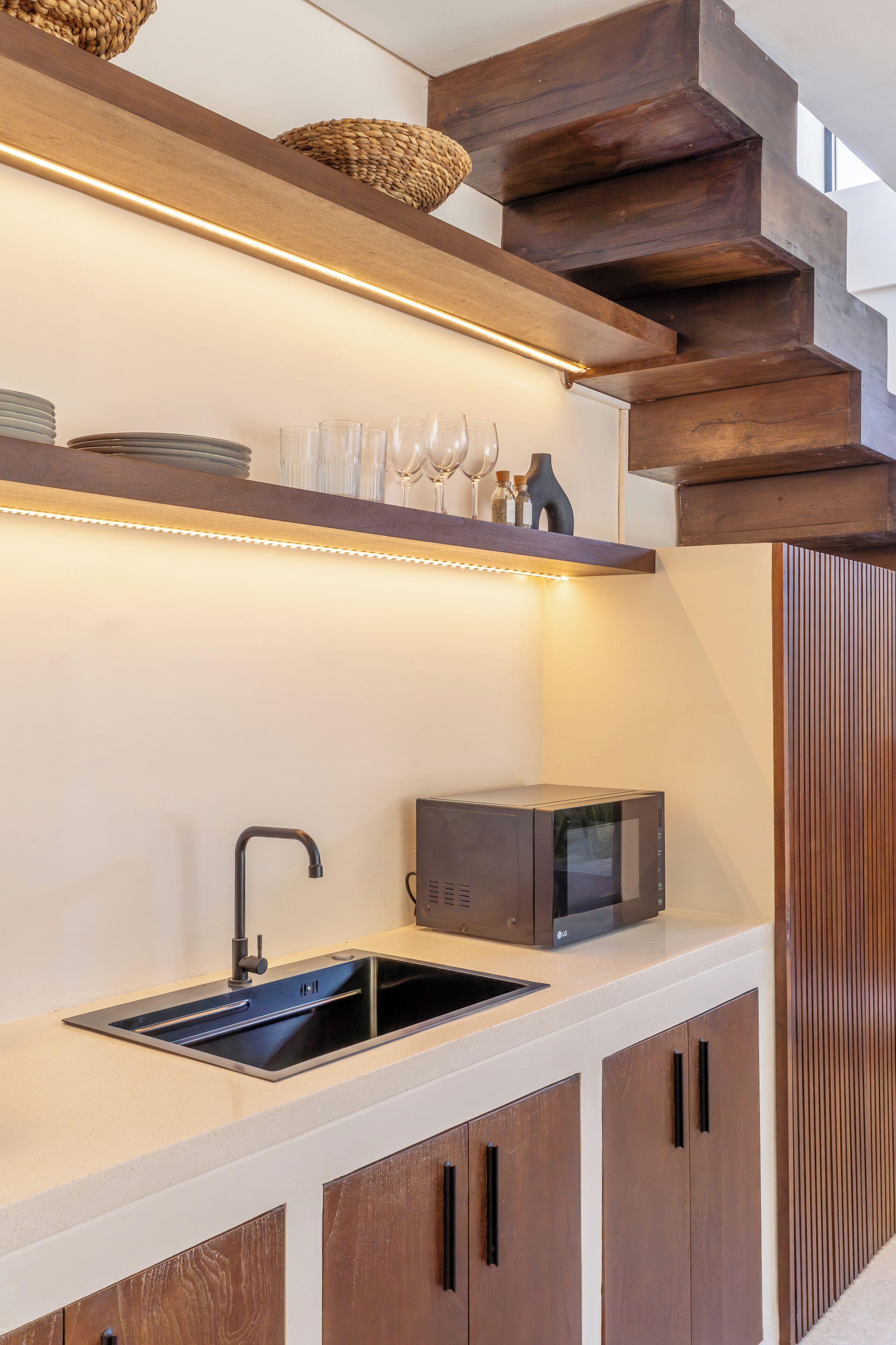 A modern kitchen with a built-in microwave, a sink, and wooden cabinets.