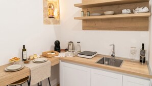 A modern kitchen with a stone accent wall, wooden shelves, a sink, and various kitchen appliances.