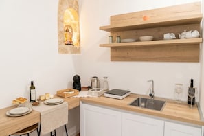 A modern kitchen with a stone accent wall, wooden shelves, a sink, and various kitchen appliances.