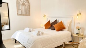 A neatly made bed with pillows, a bedside table with a lamp, and a wall-mounted light fixture. - Tresca Charme - Suite 11 Elegant Stay in the Heart of Bari (Bari)