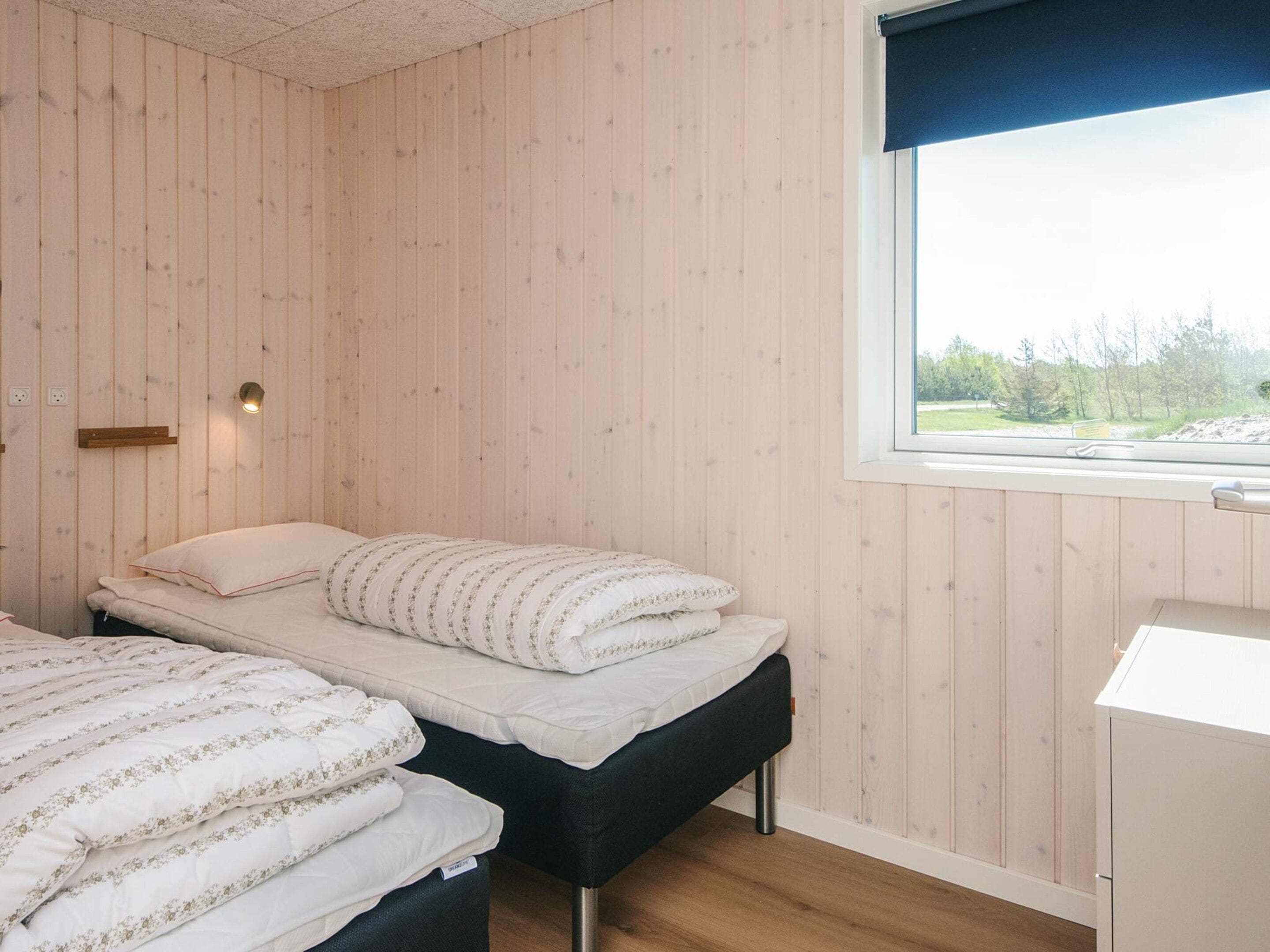 Ein Schlafzimmer mit zwei Betten, einem Fenster mit Blick und einer Wandleuchte.