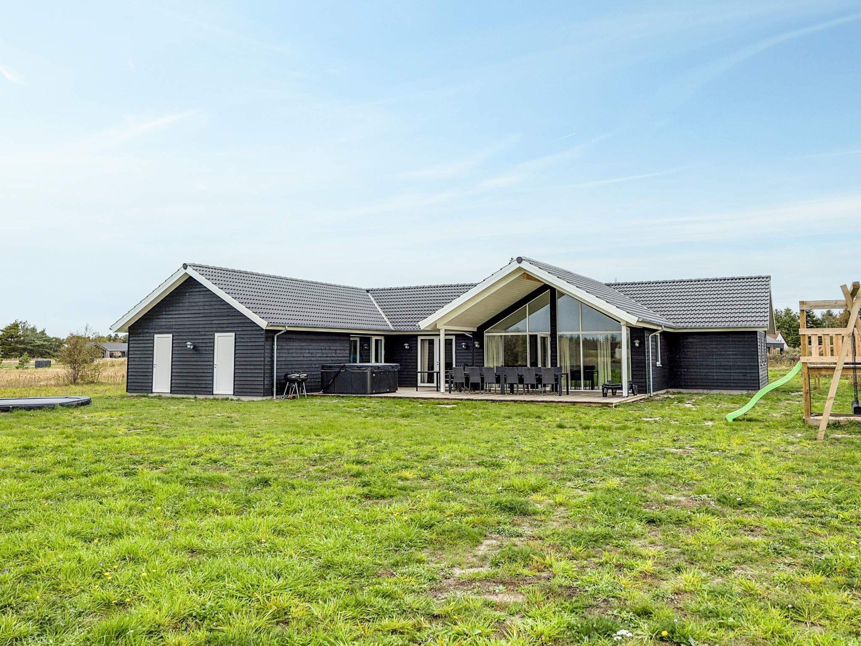 A modern two-story house with a covered patio area, a swimming pool, and a grassy yard.