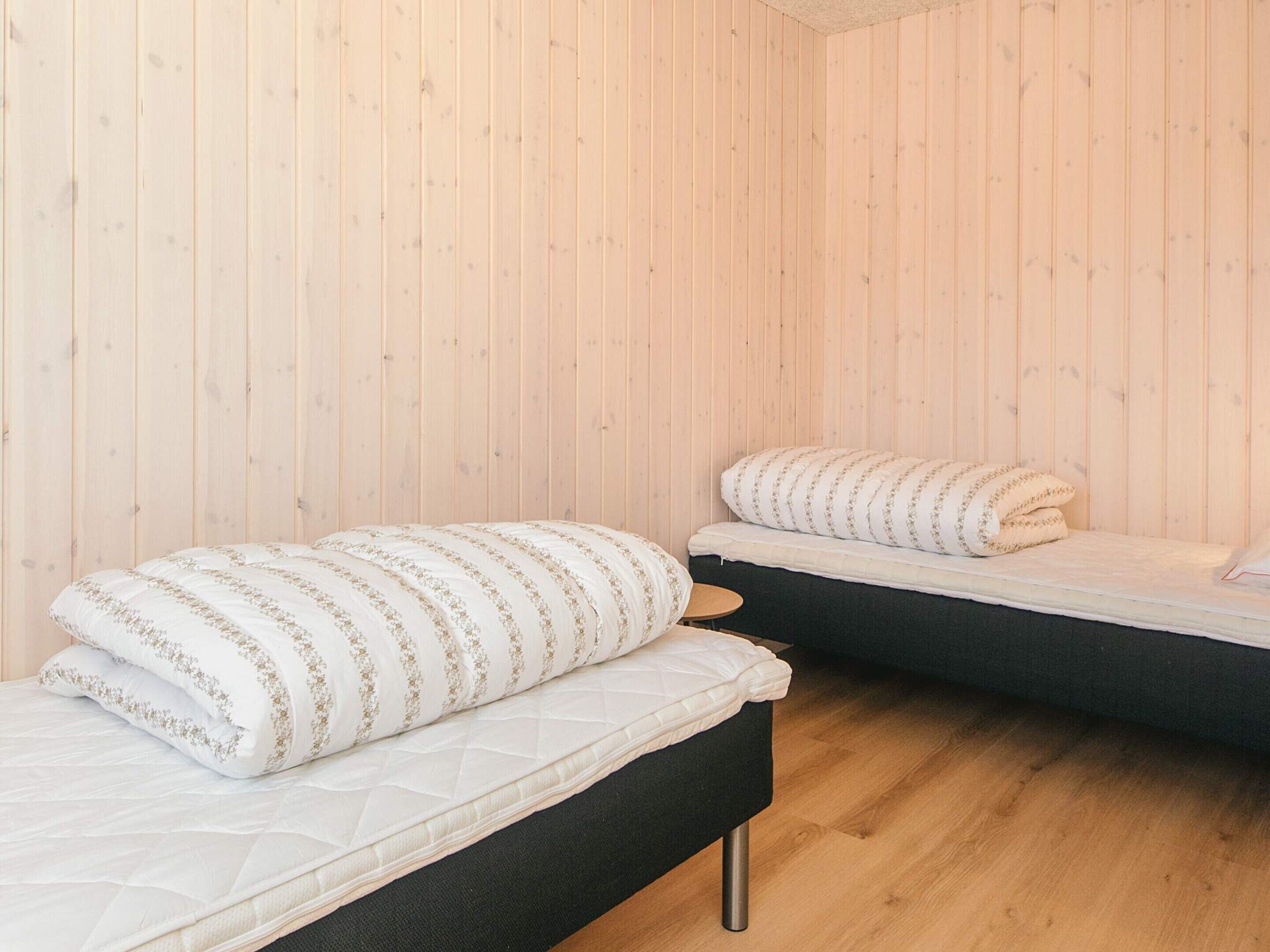 A room with two beds, wooden walls, and a small round table.