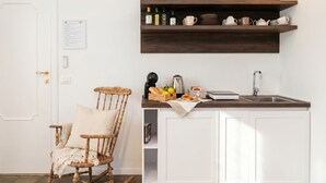 A kitchen with white cabinets, a wooden shelf with kitchenware, a rocking chair, and a door with a lock. - Tresca Charme - Suite 22-Suite with Private Terrace (Bari)