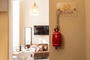 A room with a dining table set, a sofa, a television, and a sign indicating room number 22. - Tresca Charme - Suite 22-Suite with Private Terrace (Bari)