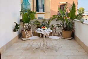 A small outdoor patio with a round table and two chairs, surrounded by potted plants. - Tresca Charme - Suite 22-Suite with Private Terrace (Bari)
