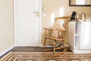 A room with a wooden rocking chair, a white door, a thermostat, and a coffee maker on a counter. - Tresca Charme - Suite 22-Suite with Private Terrace (Bari)