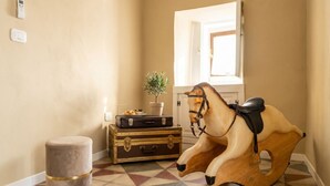 A hallway with a patterned floor, a wooden rocking horse, a small stool, and a potted plant. - Tresca Charme - Suite 22-Suite with Private Terrace (Bari)