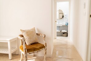 A chair with a cushion, a white bench, and a bathroom in the background. - Tresca Charme - Suite 22-Suite with Private Terrace (Bari)