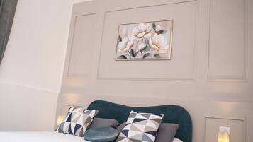 A bedroom with a bed, pillows, a wall-mounted artwork, and a bedside lamp.