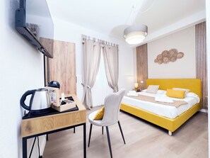 Ein Hotelzimmer mit Bett, Schreibtisch, Stuhl, Wasserkocher und Lampe.