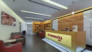 Ett modernt entréområde för spa-anläggningen, med en receptionsdisk märkt med texten ”Dreamworks Spa”, en sittgrupp med soffor och ett konstverk som hänger på väggen.