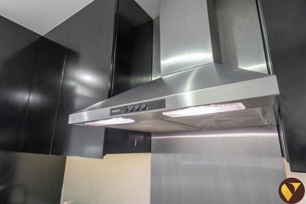 A kitchen with a stainless steel range hood and black cabinets.