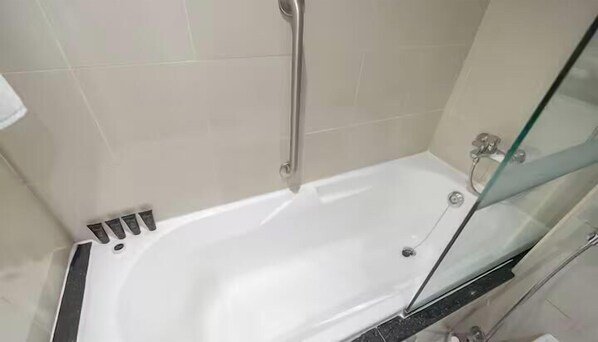 Une salle de bain moderne avec une baignoire blanche, une douche en verre et un mur recouvert de carreaux.