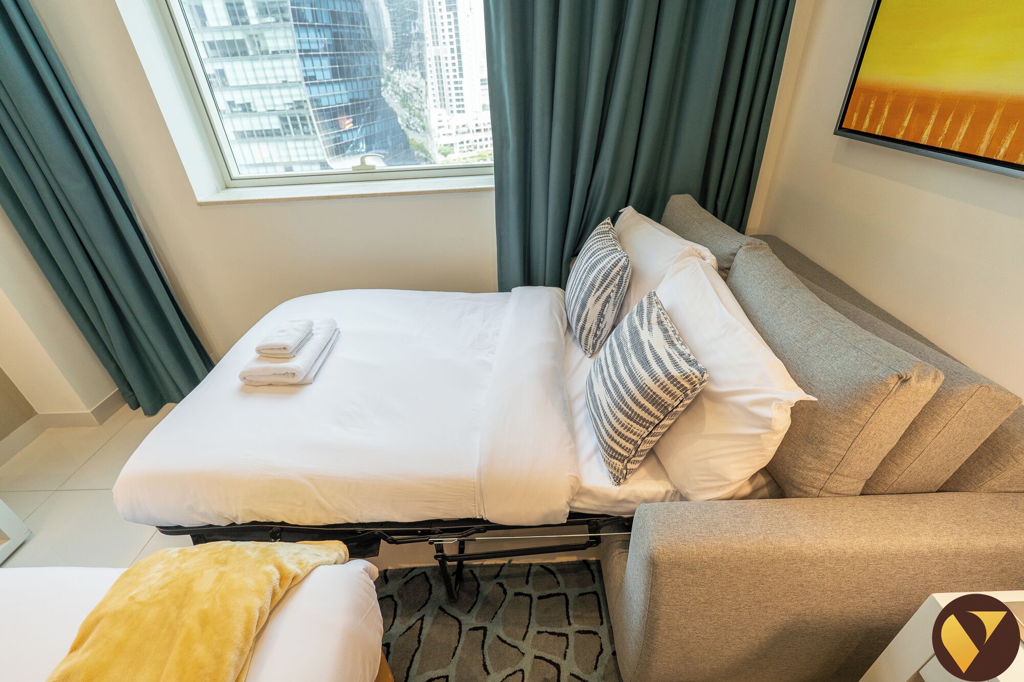 Une chambre d’hôtel avec un lit, un canapé, une fenêtre avec des rideaux et une vue sur la ville.