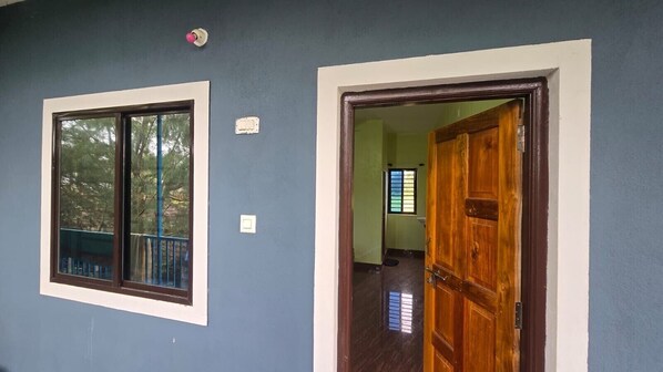 Um quarto com janela, porta e interruptor de luz na parede.