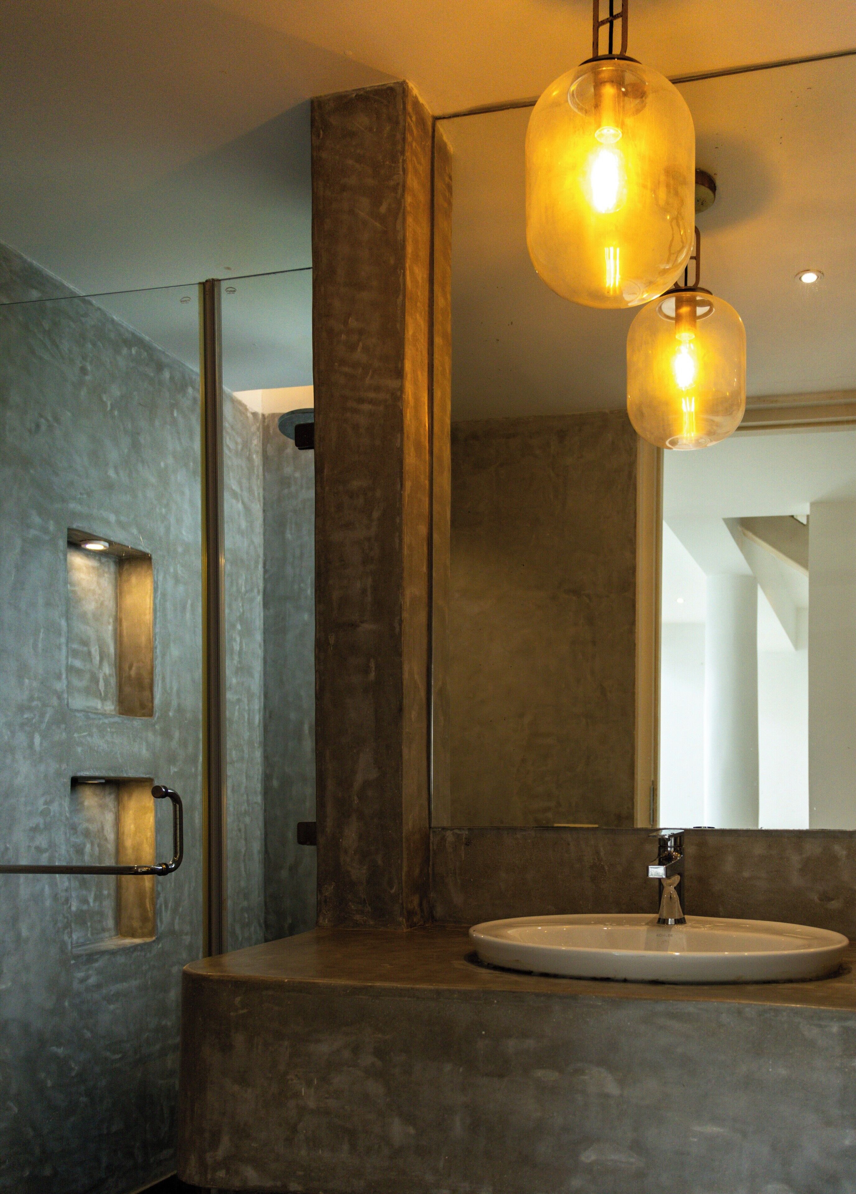 A modern bathroom with a large mirror, a round sink, and two pendant lights.